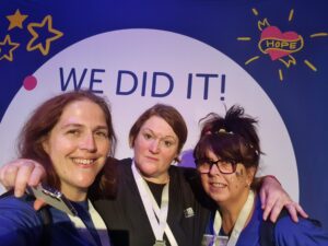 three staff members posing at a 'we did it' sign after completing a walking marathon