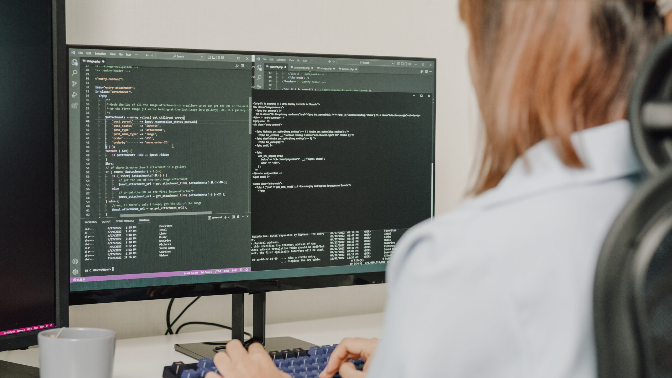Closeup of young Asian woman software developers using computer to write code sitting at desk with multiple screens work remotely at home. Programmer development concept.