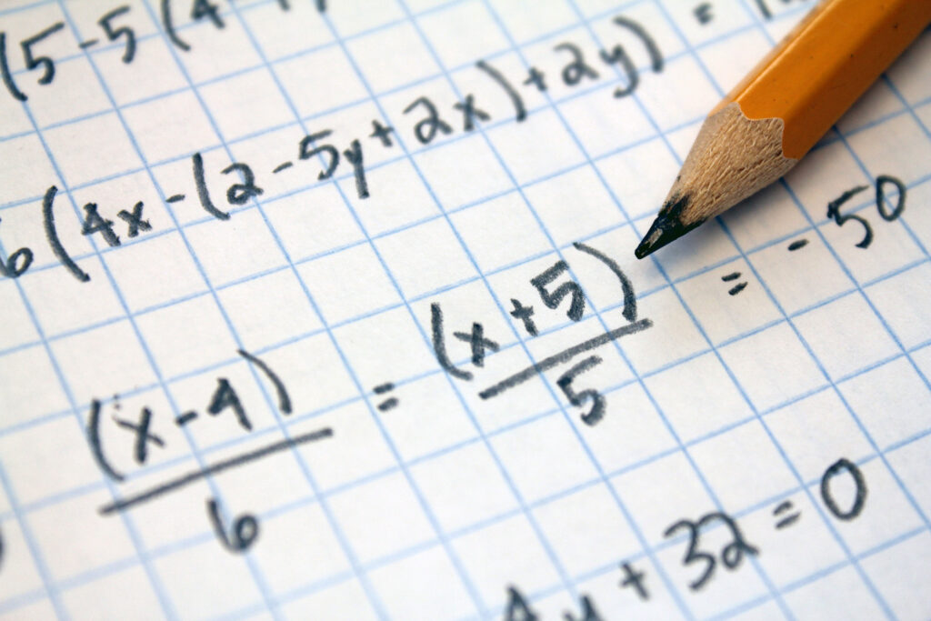 Mathematical equations seen written on graph paper with pencil.