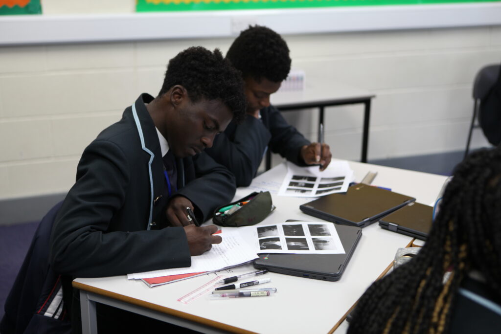 Three Year 11 Leigh Academy Ebbsfleet students are seen concentrating on their work, whilst sat at their desks during a Macbeth Workshop.