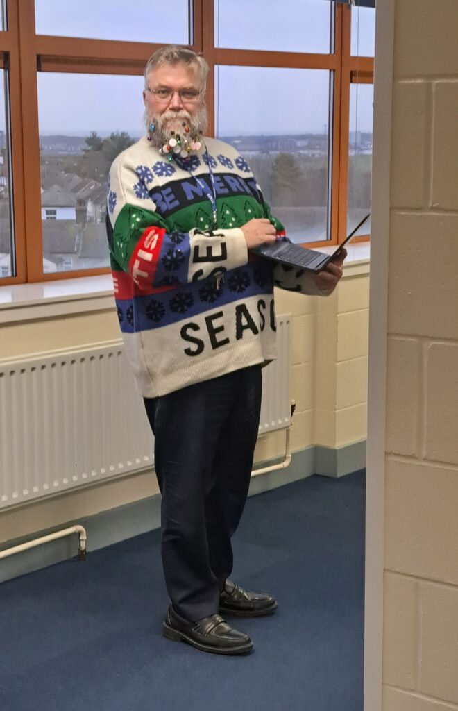 A member of staff is pictured smiling for the camera and wearing his Christmas jumper in celebration of Christmas Jumper Day 2023.