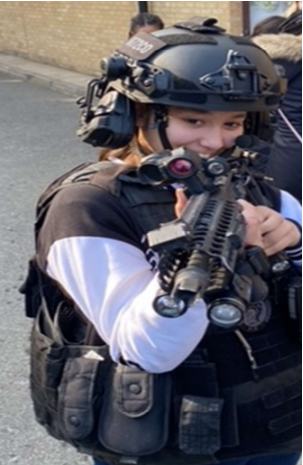 Student stood in tactical gear pretending to shoot at something at a Met Police event