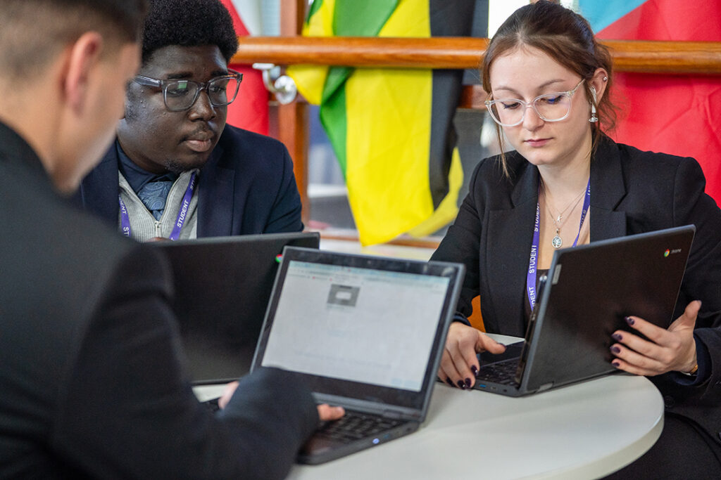 Three students sitting at a table with laptops